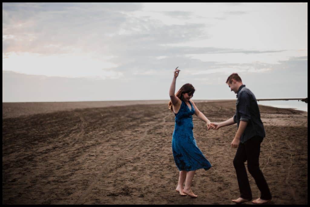 Young couple dance on the black sand at Karekare Beach.