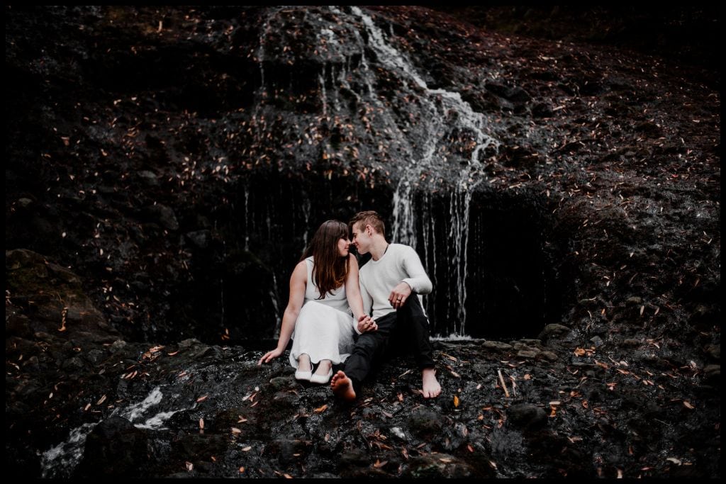 Young couple sit perched on the edge of the Opal Pool Stream Cascade.