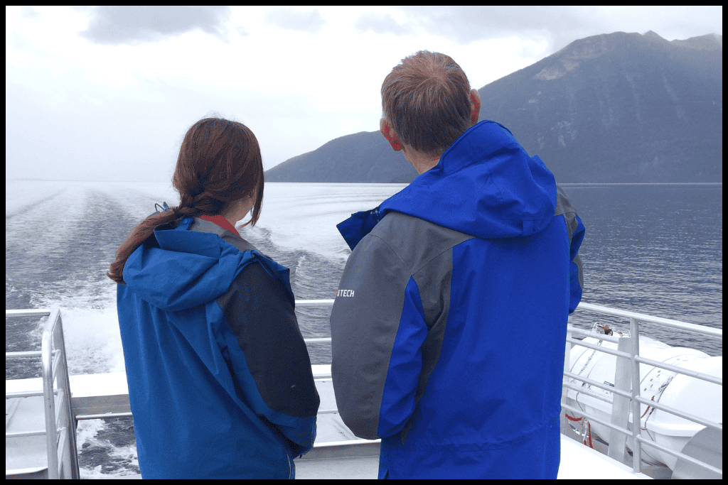 Two figures face away from the camera as the Te Anau Downs boat shuttles them up Lake Te Anau to Glade Wharf to start the Milford Track.