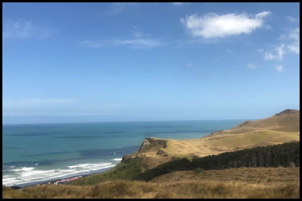Kariotahi Beach, taken from up the road with some of the coastal cliffs in the foreground.