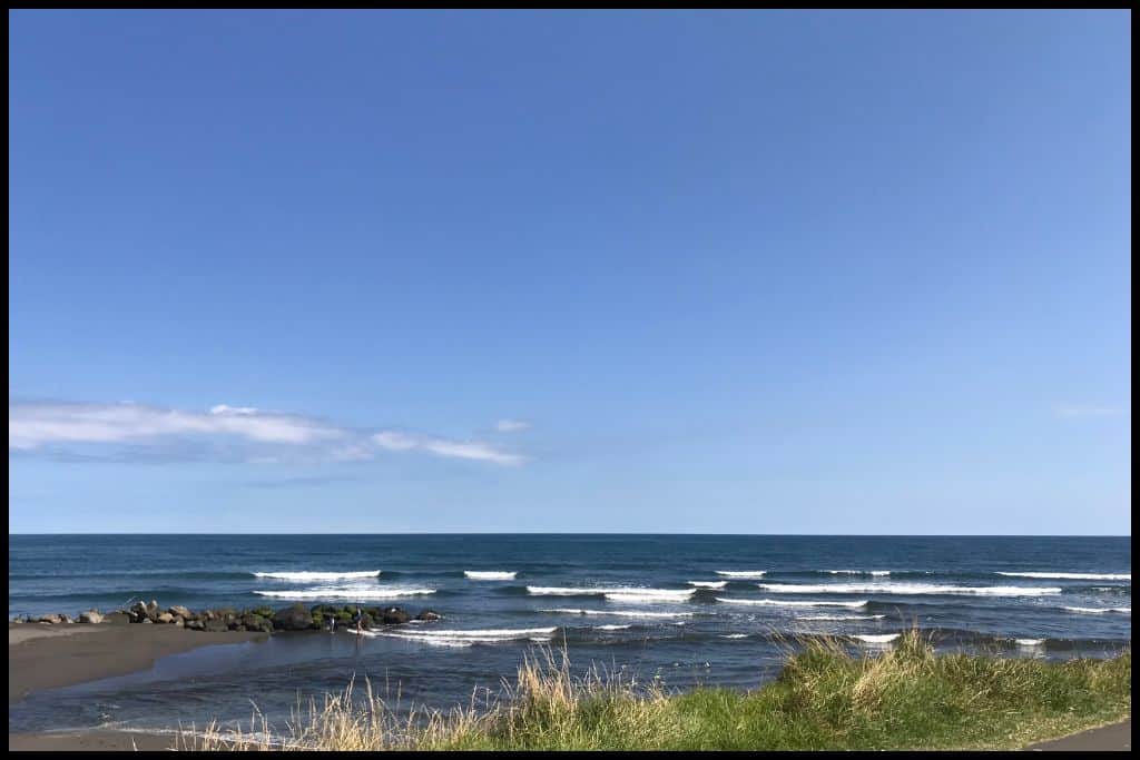 Black sand Bell Block Beach, with its dark blue surf under a summer sky.