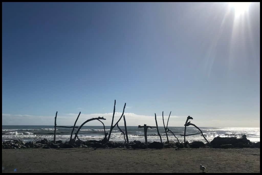 Pieces of driftwood stuck into the sand at different angles read HOKITIKA. It's now a long-standing sculpture on Hokitika Beach.