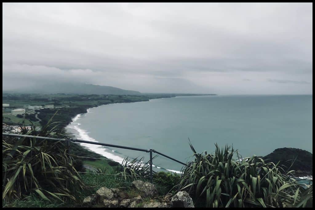 A high angle shot taken from Paritutu Rock shows Paritutu Beach on a gloomy day.