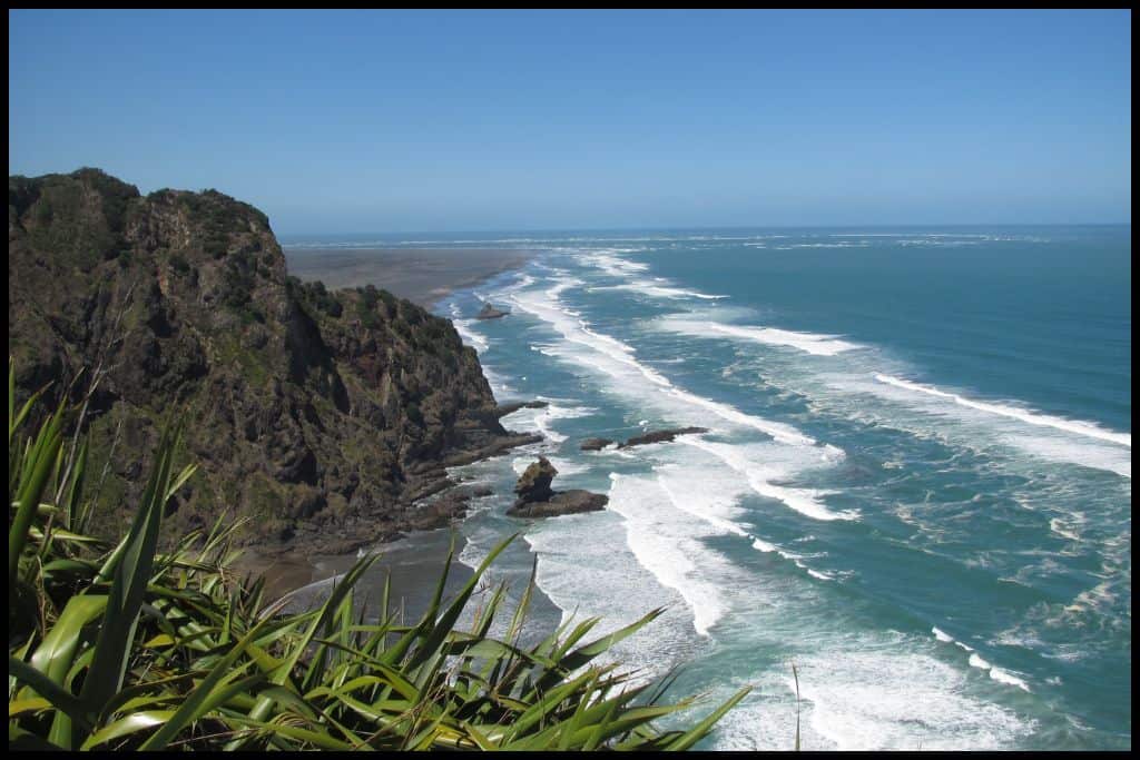 Blue surf washes up on the black sands of the beaches south of Piha.