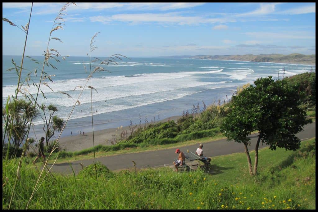 Photo shows the vantage point from Wainui Reserve Bush Park looking down the green hillside and over the rolling Raglan surf.