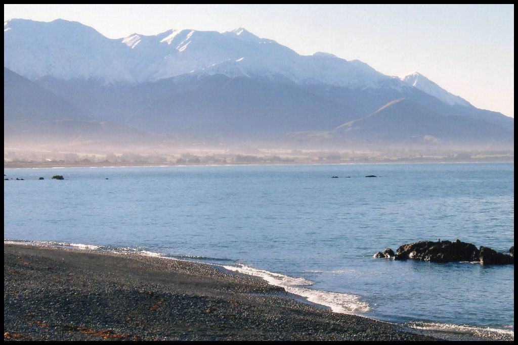 A Kaikōura beach, with volcanic black pebbles instead of sand (and snowy mountains in the background).