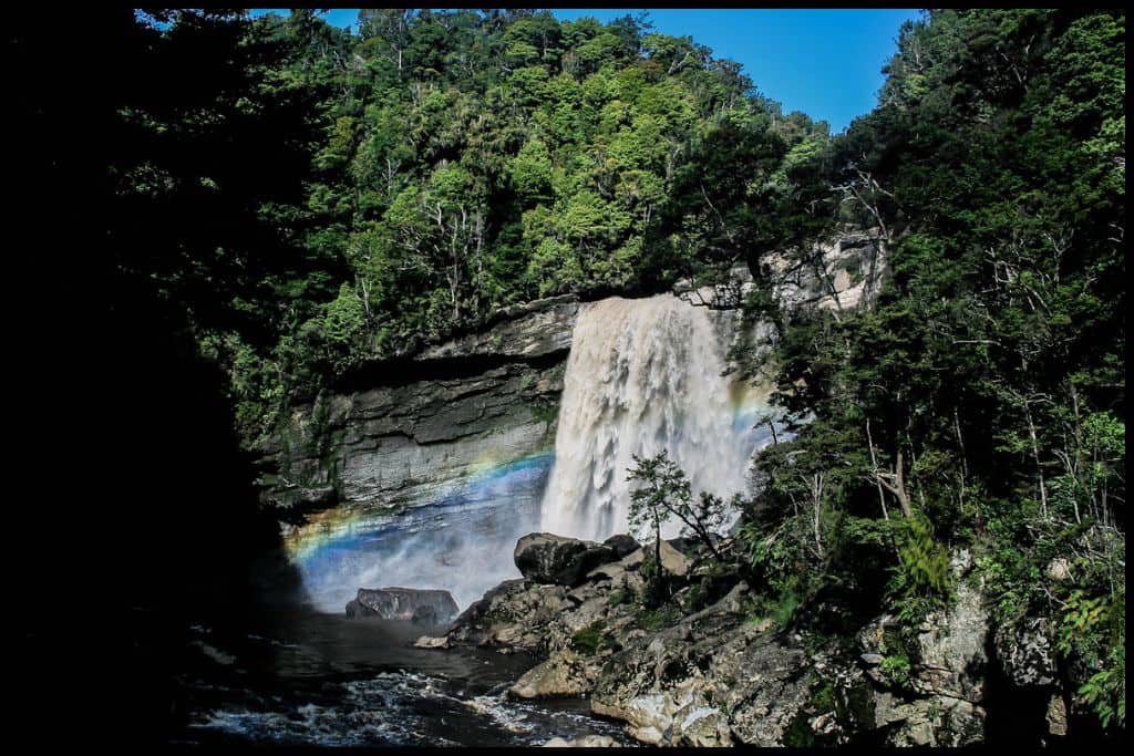A rainbow stretches across the spray of Mangatini Falls.