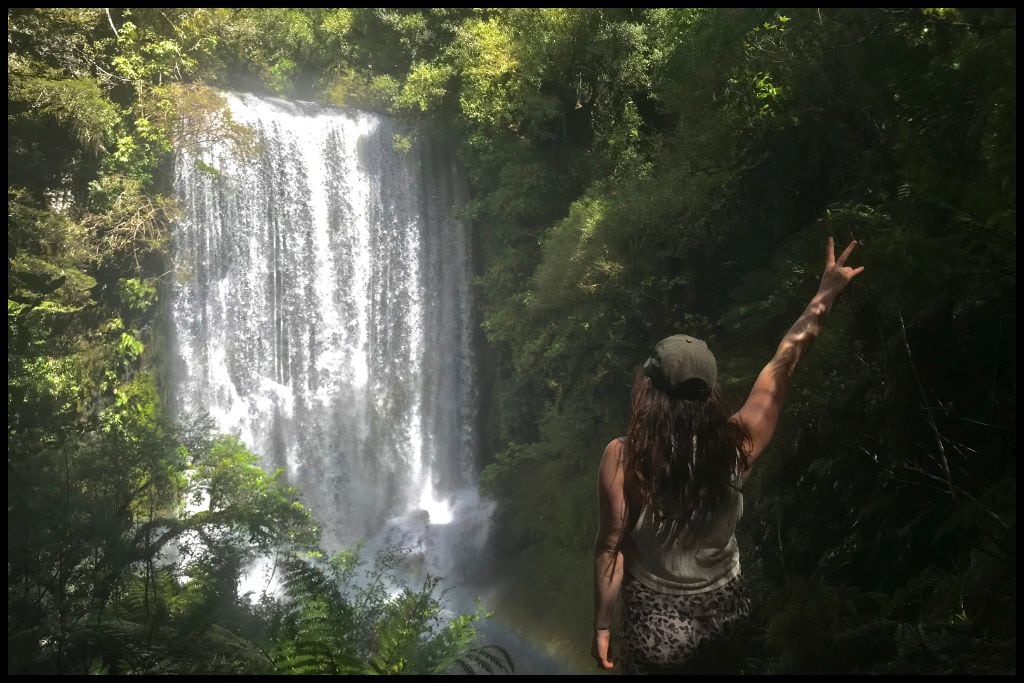 A young woman stands with up raised up looking down over Korokoro Falls on the Lake Waikaremoana Track.