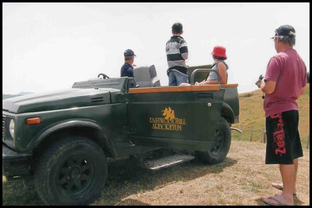 A shot of an Eastwoodhill Aboretum four wheel drive vehicle parked on a hill with its passengers looking out.