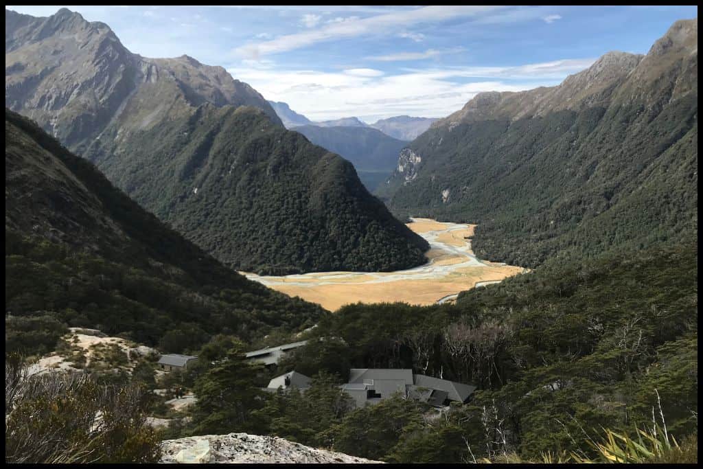 Photo looks down on the Routeburn Flats and surrounding mountains with Routeburn Falls Hut nestled in the bushline down below.
