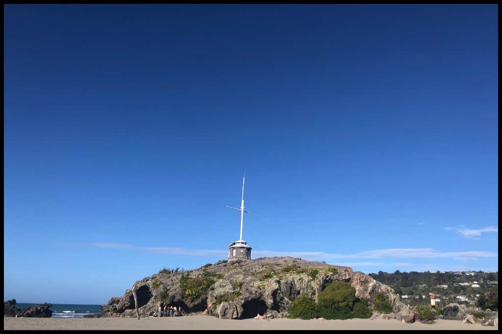 The flagpole atop Cave Rock at Sumner Beach stands tall under a cobalt blue sky.