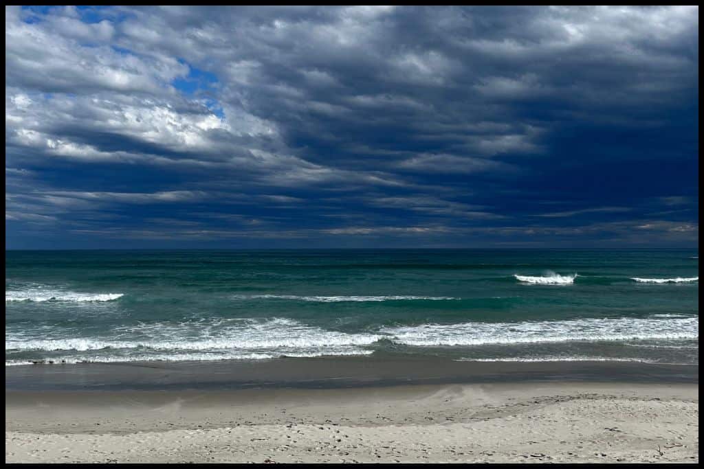 Dark stormclouds hover over deep green waves at Smaills Beach.