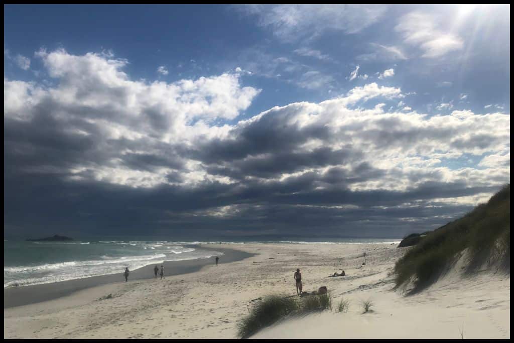 Dramatic dark storm clouds hover over the white sandy Smaills Beach.