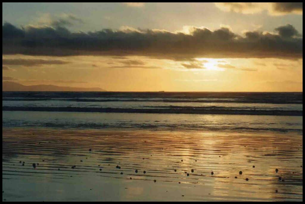 Sunset reflects off the wet sand at low tide at Oreti Beach.