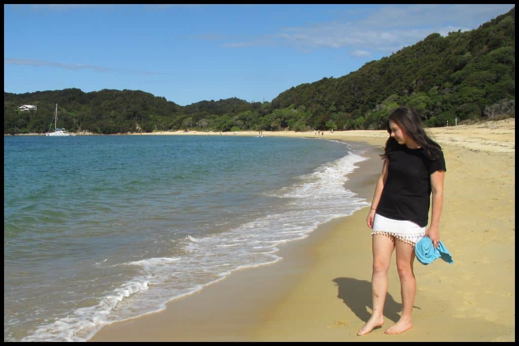 A young woman wanders down to the shoreline of Anchorage Bay as the water laps onto the golden sand.