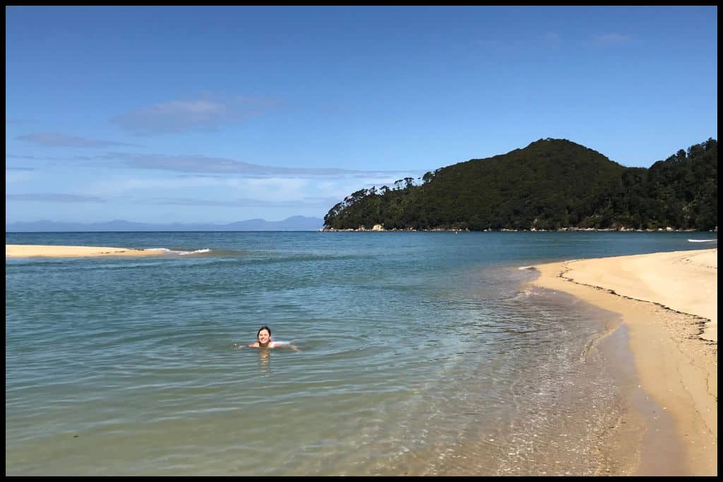 A young woman swims toward the camera in very pretty, clear waters.