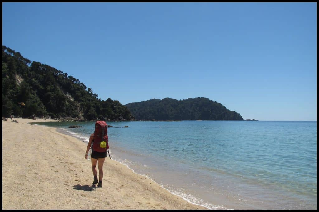 A lone hiker recedes down one of Abel Tasman National Park's beaches.