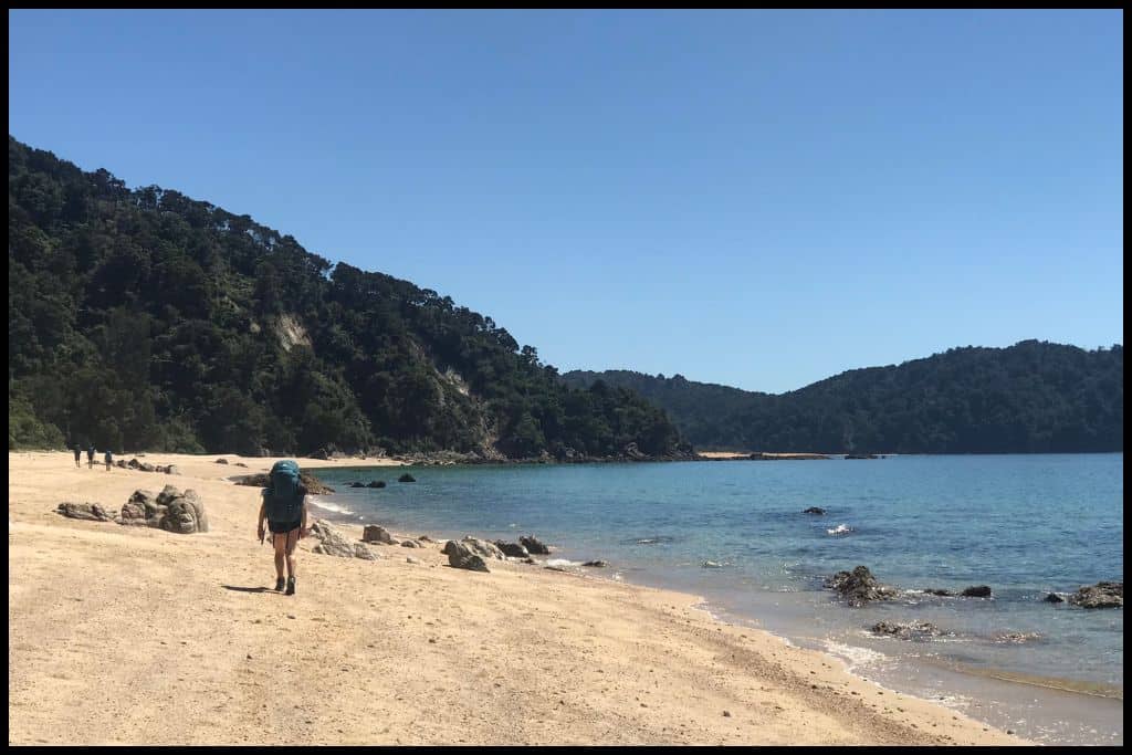 A lone hiker recedes down one of Abel Tasman National Park's beaches.
