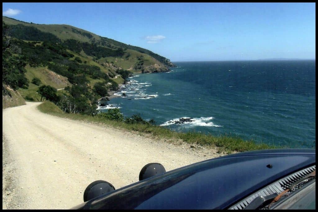 The photo shows the bonnet of a jeep and the one way road ahead, on the windy route around the top of the Coromandel Peninsula.