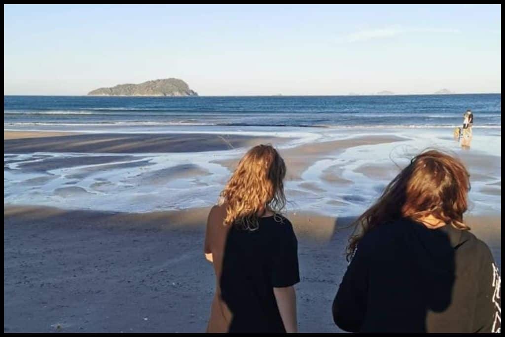 Two girls head down to the water's edge during a low tide at Pauanui Beach.