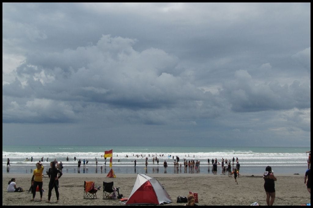 A crowded beach during peak season in Raglan.