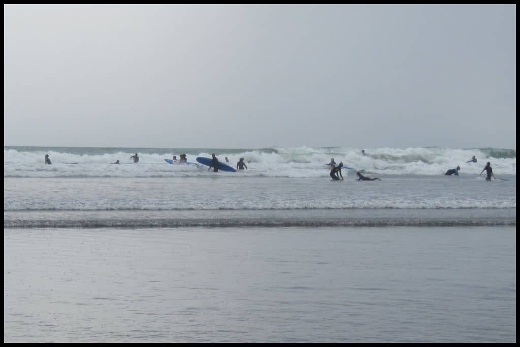 Pro and amateur surfies dotted amongst the Raglan surf on a grey day.