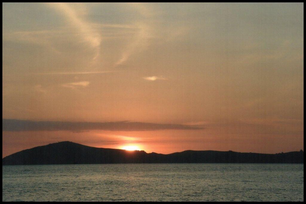 Sunset at Shelly Beach: sun sinks behind the silhouette of an island out on the water.