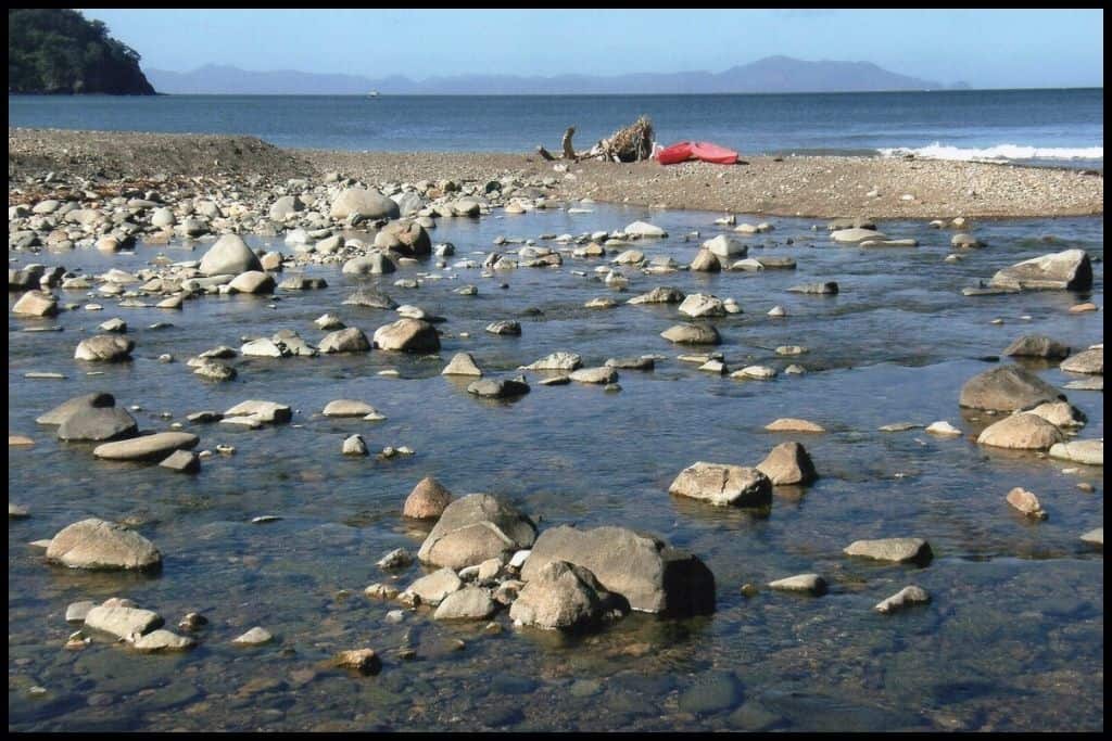Photo captures the stones and shallow water on the shoreline of Stony Bay.