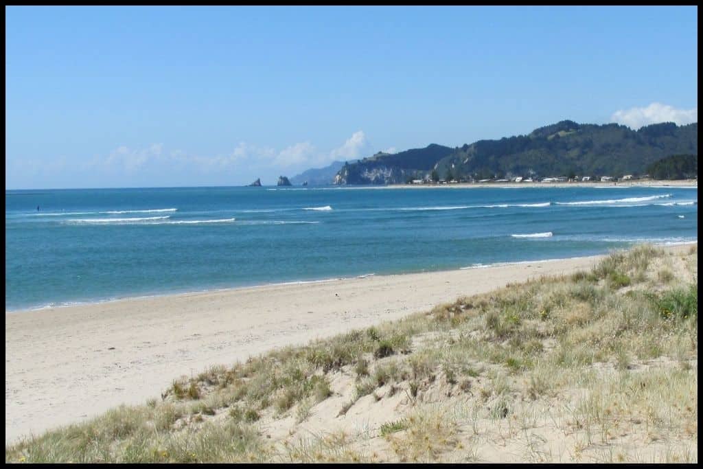 White sand leads out in an arc toward the headlands of Whangamata Beach.