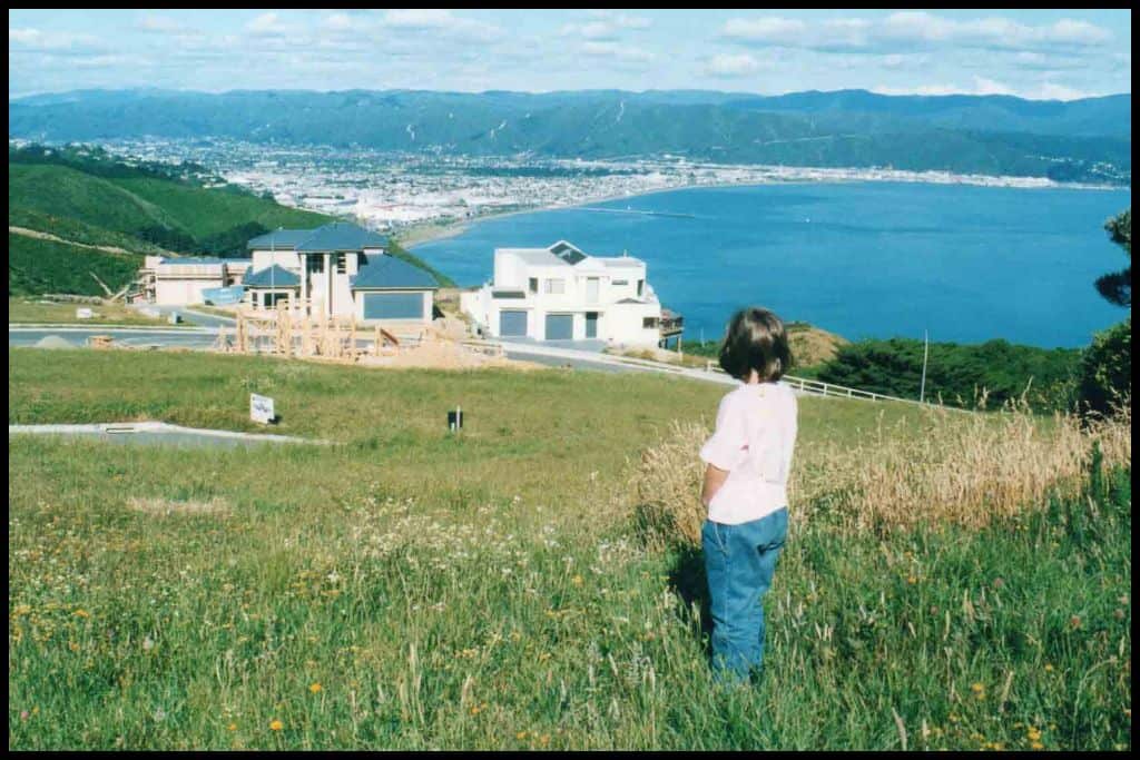 Young girl looks out over a building site and Wellington Harbour from Newlands, a new sub division.