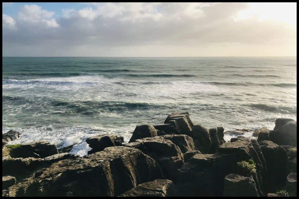 Punakaiki Pancake Rocks, pictured from above with ocean waves pounding against them.