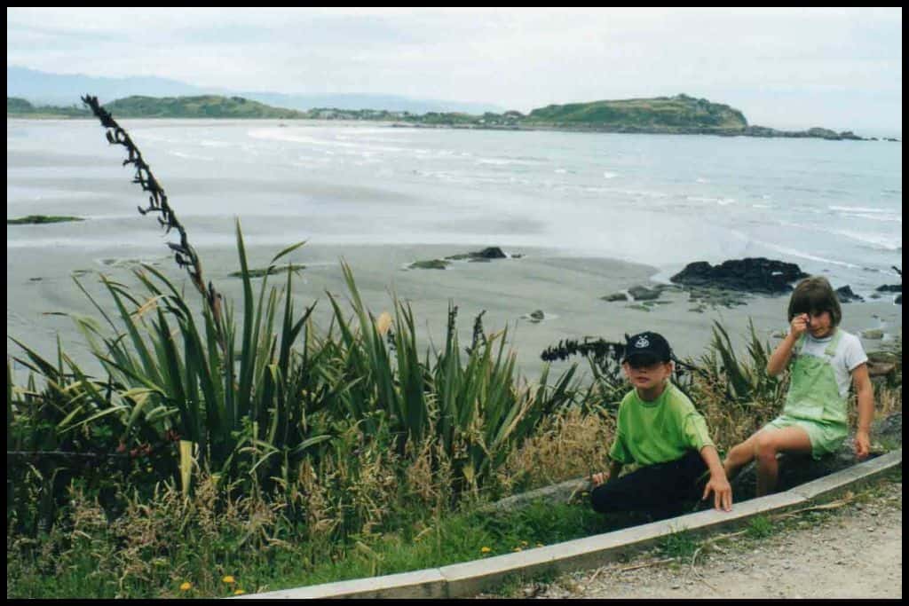 Two children sit for the camera with the Westport coastline behind them.